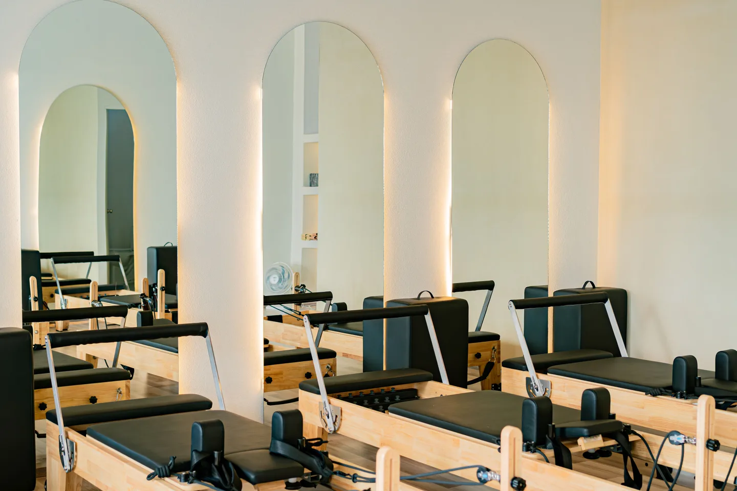 Plusieurs appareils Reformer disposés devant les miroirs d’un studio de Pilates