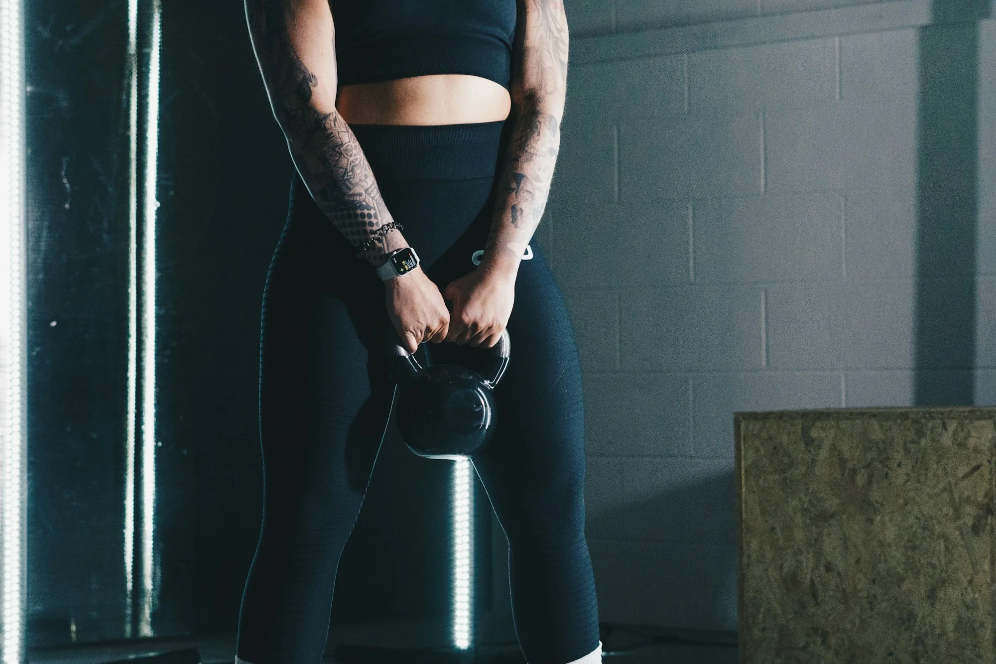 Une personne tient une kettlebell dans une salle d’entraînement